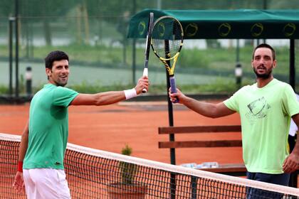 Novak Djokovic y Viktor Troicki chocan raquetas durante una práctica de tenis en Serbia; ambos superaron el coronavirus.