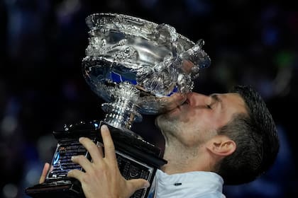Novak Djokovic besa el trofeo de campeón del Abierto de Australia tras derrotar a Stefanos Tsitsipas en la final el 29 de enero de 2023, en Melbourne