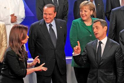 Cristina Kirchner y el expresidente de Francia Nicolas Sarkozy (R), hacen gestos mientras el exprimer ministro de Italia, Silvio Berlusconi, y Angela Merkel observan la escena durante la tradicional foto de familia en Cannes