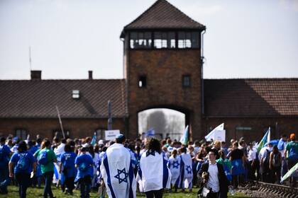 Numerosos jóvenes ataviados con banderas israelíes participan en una marcha en el Día del recuerdo del Holocausto
