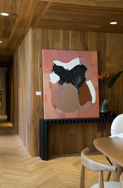 Obra de Agustina Ponce, “Formas y Espacios” (Diderot.art) sobre revestimiento de madera (Patagonia Flooring). Consola (El Camino Studio).