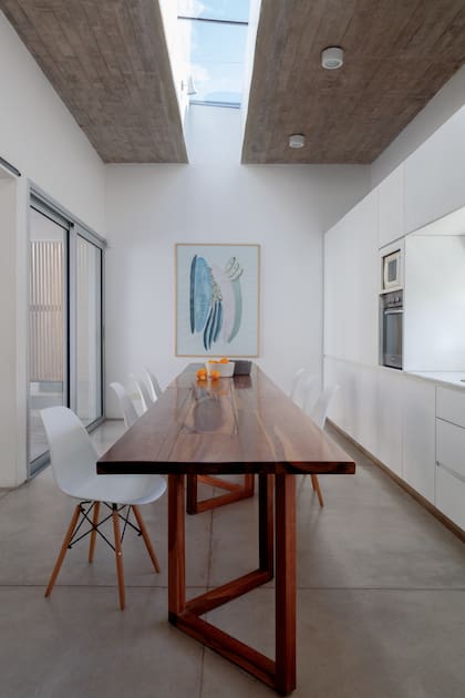 Obra de la artista Mili D’Aiello en acuarela hecha con tintes naturales. La raja en el techo de hormigón le da luz natural a la mesa y enfatiza la disposición longitudinal del espacio.