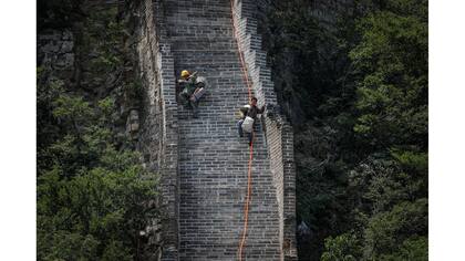 Obreros bajan por la sección Jiankou de la Gran Muralla llevando sus herramientas y pertenencias