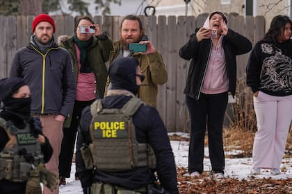 Observadores graban mientras agentes federales llevan a cabo una redada migratoria, el jueves 5 de febrero de 2026, en Minneapolis