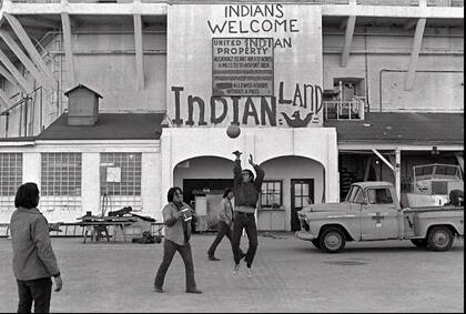 Ocupas jugando afuera del muro de la prisión, donde habían modificado el cartel que solía decir "Propiedad de los Estados Unidos" a "Propiedad de los indios unidos".