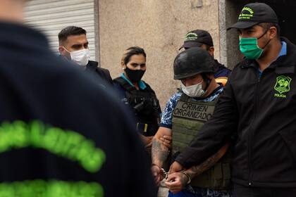 Oficiales de policía escoltan a Joaquín Aquino, también conocido como "El Paisa", acusado de distribuir cocaína adulterada en José C. Paz, el 3 de febrero de 2022