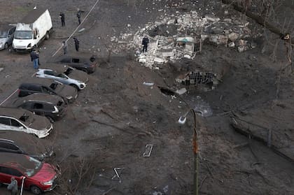 Oficiales de policía inspeccionan un cráter causado por una explosión después de un ataque con misiles en Kiev, el 21 de marzo de 2024.