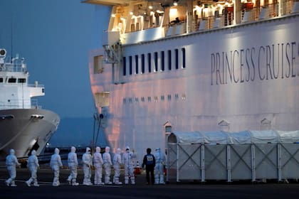 Oficiales vestidos con trajes protectores entran al crucero Diamond Princess que reportó contagios de Covid-19 al amarrar en la terminal de Yokohama al sur de Tokio el 7 de Febrero
