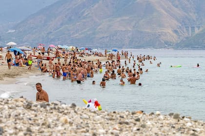 La gente disfruta del mar en la playa de Torre Faro durante un caluroso día de verano en Sicilia, el 11 de agosto de 2021. (Fotografía de Giovanni ISOLINO / AFP)