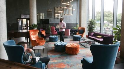 Old Oak se destaca por sus amplios espacios comunes de estilo industrial, adornados con sillones coloridos y muebles de madera.