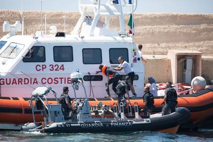 Guardias costeros transportan a un inmigrante al puerto de Lampedusa desde el barco "Open Arms" de la ONG que lleva el mismo nombre 