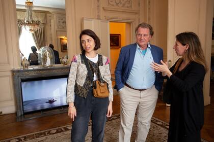 Anfitrión, el embajador Sersale junto con la curadora Melina Berkenwald (URRA) y Camila Charask; como en cada rincón, en la chimenea, una pantalla