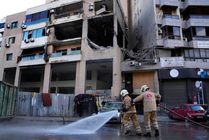 Operarios de las fuerzas de defensa civil limpian la calle frente a un edificio residencial donde un presunto ataque israelí mató a un alto cargo político de Hamas, Saleh al-Arouri, en un suburbio del sur de Beirut, que es un feudo del grupo Hezbollah, en el Líbano, el 3 de enero de 2024. (AP Foto/Hussein Malla)