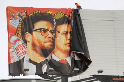 Operarios descuelgan un cartel promocional de la película Una loca entrevista (The Inverview)