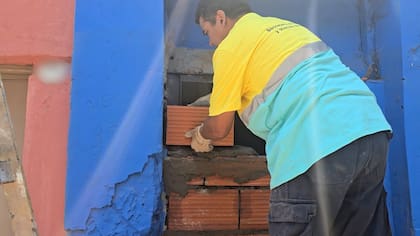 Operarios refuerzan la pared tapiada en la entrada del inmueble, sobre andamios improvisados, para impedir nuevas usurpaciones