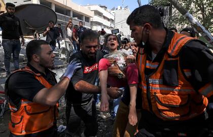 OPSHOT - Palestinian paramedics evacuate a girl from the rubble of a destroyed building in Gaza City's Rimal residential district on May 16, 2021, following massive Israeli bombardment on the Hamas-controlled enclave. - Israel's army said it had bombed the home of the political leader of Islamist group Hamas in the Gaza Strip, as the UN Security Council was to meet amid global alarm about the escalating conflict. (Photo by MAHMUD HAMS / AFP)