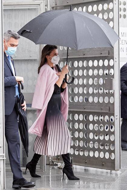 Optó por un look con una falda plisada de efecto degradé en negro y rosa de Reiss, que combinó con un top manga larga al cuerpo y botas de Steven Madden. Completó el outfit con un abrigo rosa y clutch negro Carolina Herrera y joyas Chanel. También llevó el barbijo médico.