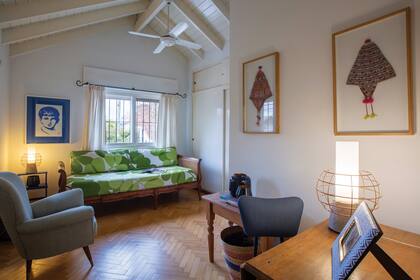 Otro de los cuartos, reconvertido en rincón de home office y espacio de lectura. El acolchado con estampa tropical, traído de su luna de miel en Hawái, y el cuadro de Diego Roa, le suman alegría.