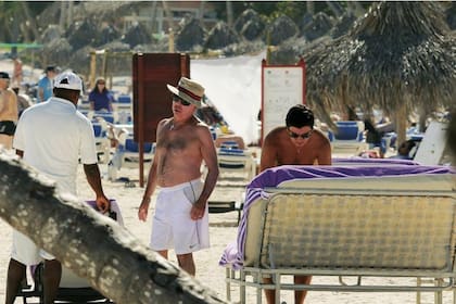 Oyarbide en la playa privada del hotel, a su lado, de lentes oscuros, Claudio Blanco, su acompañante