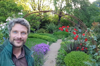 Paisajista en su paisaje: Nicolás Heinen debajo del arco de rosas trepadoras que conecta el rosedal con el jardín ubicado en el fondo del terreno.