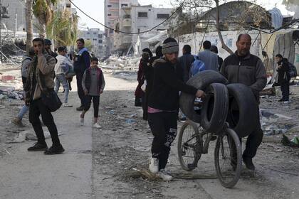 Palestinos caminan en medio de la destrucción causada por los bombardeos israelíes en el campo de refugiados de Nuseirat en la Franja de Gaza.(AP Photo/Adel Hana)