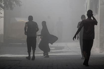 Palestinos caminan en medio del humo tras una operación israelí en Nuseirat
