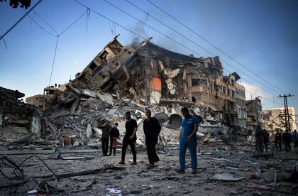 Palestinos caminan junto a los restos de un edificio de 15 pisos destruido después de ser golpeados por ataques aéreos israelíes en la ciudad de Gaza.