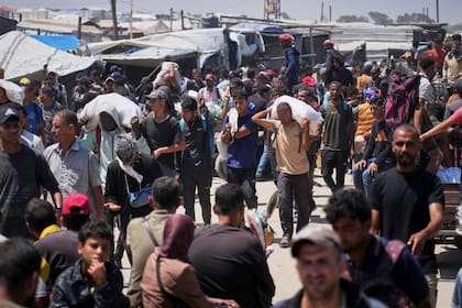 Palestinos cargan bolsas que contienen ayuda humanitaria en Rafah, en el sur de la Franja de Gaza