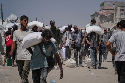 Palestinos cargan sacos de harina descargados por un convoy de ayuda humanitaria que llegó a Ciudad de Gaza desde el norte de la Franja de Gaza, el domingo 27 de julio de 2025.