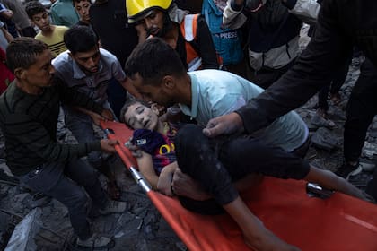 Palestinos evacuan a los heridos tras un bombardeo que destruyó un edificio en Khan Younis, en la Franja de Gaza, el 19 de octubre de 2023. (AP Foto/Fatima Shbair)