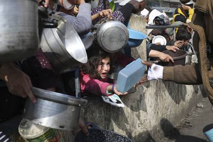 Palestinos hacen fila para obtener alimentos gratuitos durante la ofensiva aérea y terrestre en curso de Israel en la Franja de Gaza en Rafah, el martes 9 de enero de 2024. 