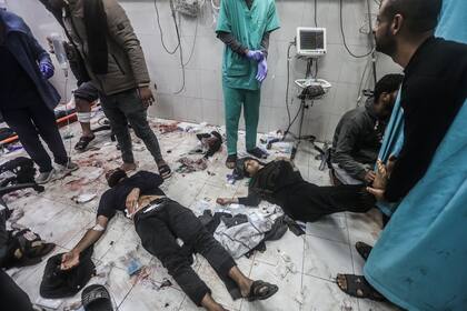 Palestinos, heridos durante un bombardeo israelí, reciben tratamiento tumbados en el suelo del Hospital Nasser.