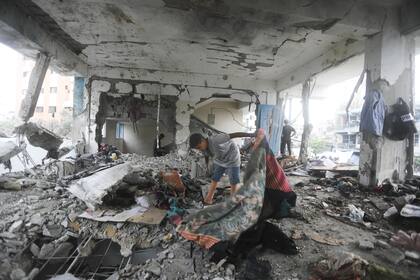 Palestinos inspeccionan los daños después de un ataque aéreo israelí contra una escuela para personas desplazadas de la ONU. (AP/Ismael Abu Dayyah)