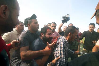 Palestinos llevan a un civil israelí capturado desde el kibbutz Kfar Azza a la Franja de Gaza
