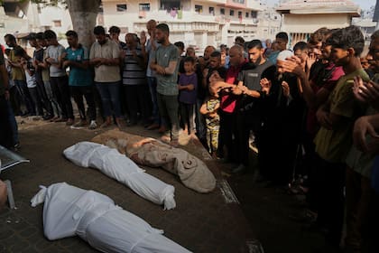 Palestinos rezan junto a los cuerpos de familiares muertos en un ataque aéreo israelí en la Franja de Gaza, durante su funeral en el exterior de la morgue del hospital de Shifa, en la Ciudad de Gaza, el 26 de julio de 2025. (AP Foto/Abdel Kareem Hana)