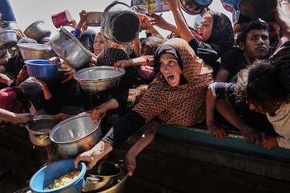 Palestinos tratan de obtener comida donada en una cocina comunitaria Jan Yunis, en el sur de la Franja de Gaza, el viernes 9 de mayo de 2025. (AP Foto/Abdel Kareem Hana)
