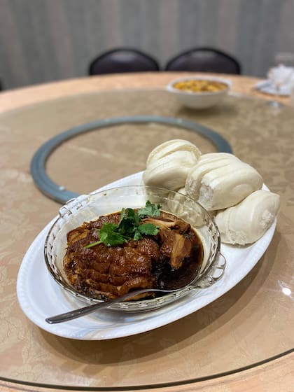 Panceta de cerdo de larga cocción con verduras secas fermentadas y especias chinas que se acompañan con panes chinos