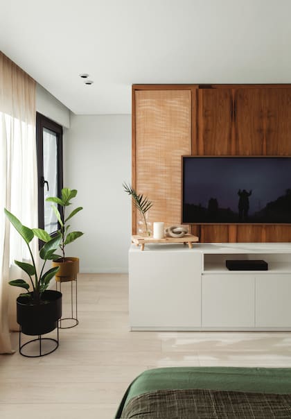 Panel de petiribí con esterilla en los laterales y cómoda en madera laqueada de blanco (Muchnik y Wainstein). Plantas y macetas (Ciudad Naturaleza).