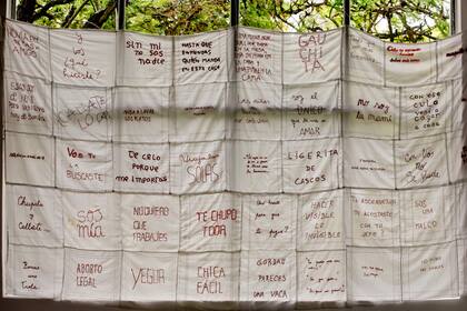 Pañuelos bordados con leyendas que alertan sobre la violencia de género reciben en el primer piso de la sala de exposiciones