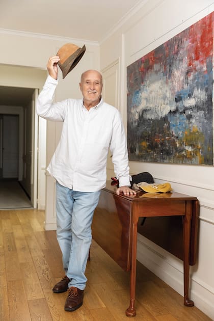 Paparella posa con un sombrero de su colección frente
a uno de los cuadros
que él pintó.