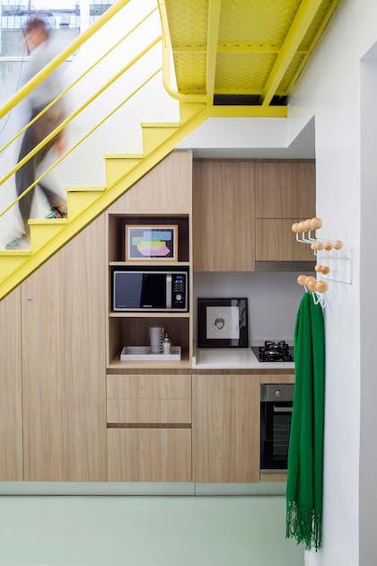 Para ampliar el espacio de guardado, Estudio Trama planteó una cocina lineal, y extendieron sus límites hacia el bajo escalera. “El piso está hecho con un material monolítico, autonivelante, que admite color y es de alto tránsito”.