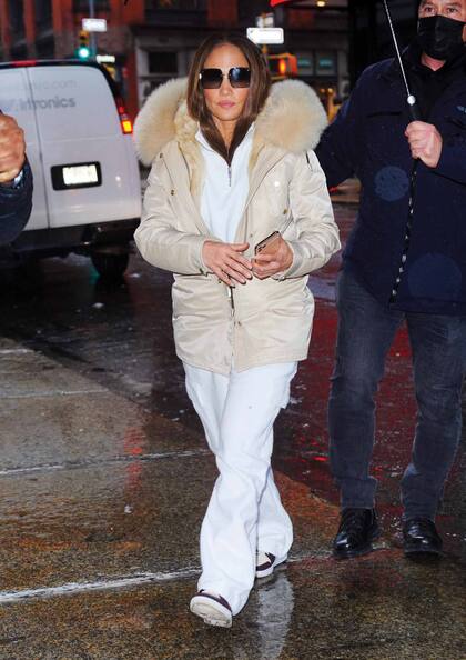 Para combatir el frío y la lluvia, JLo optó por una campera con capucha de piel, pantalón blanco y zapatillas.