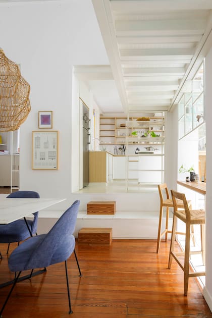 Para compensar el desnivel, combinaron escalones de pino tea con un mueble de melamina que aumenta el lugar de guardado. Barra con tapa de pino tea y vitrina colgante de hierro con estantes de vidrio.