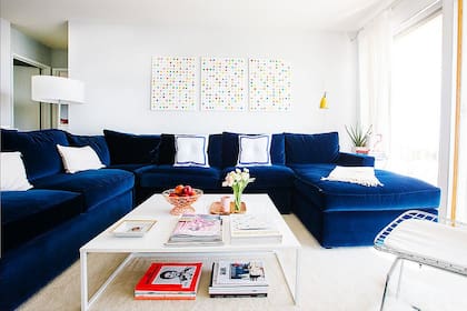 Para contrastar con la base clara, un sofá en azul Francia aterciopelado