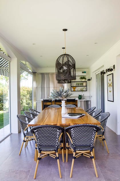 Para crear un clima relajado y elegante a la vez, sillas ‘París’ blanco y negro, y lámparas de techo de hilo natural (Agustina Cerato). Junto a la parrilla con frente de acero inoxidable, estantería de hierro negro con vajilla y objetos de cerámica