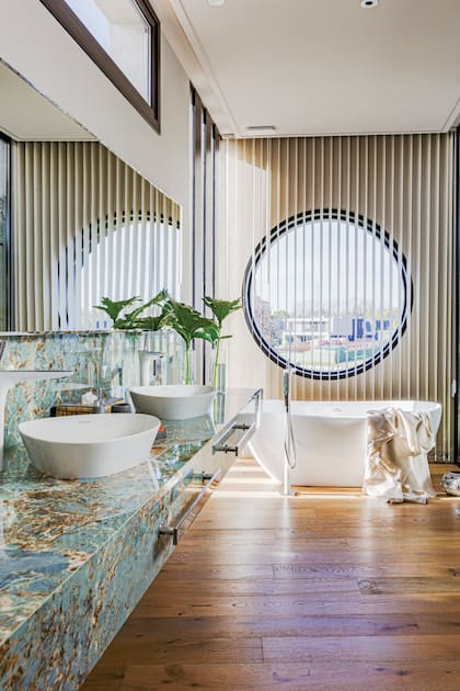 Para darle privacidad a este baño espectacular, la arquitecta Gabriela Barrionuevo eligió unas cortinas de bandas verticales (Hunter Douglas) a tono con el piso y las vetas del mármol ‘Étoile Illusion’ (SBG).