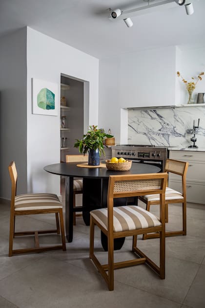 Para el comedor diario se eligió una mesa en granito ‘Brasil’ leather y sillas de esterilla de su autoría. Junto a la alacena, una obra de Guadalupe Ortega Blasco.