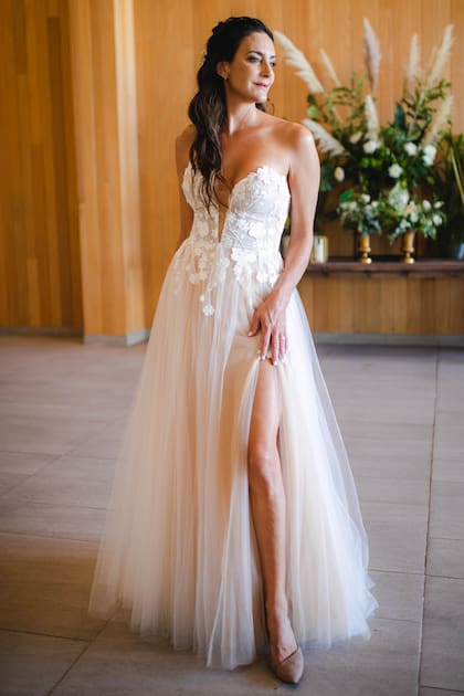 Para el gran día, Luciana eligió un vestido de la casa Nevada Novias, firmado por las diseñadoras Ingrid Mancilla y Maria jose Serrano. El modelo está confeccionado en seda y malla de seda en tonos marfil y nude, con aplicaciones bordadas en un corset y en la falda asimétrica.