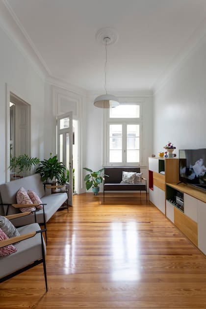 Para el living eligieron sillones (Estudio Gröber) de líneas sintéticas y potentes en tonos de gris. Los almohadones (Maraña) combinan con los nichos en verde, blanco y rojo del mueble hecho en Traë (la carpintería del hermano de Pablo) que trajeron desde Rosario. Lámpara de techo ‘Vita’ (Glitter).
