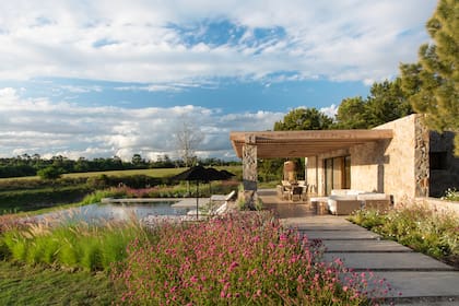 Para el quincho semicubierto, junto a la parrilla, Joanne pensó un juego de living, una mesa con sus sillas, cuatro hamacas (entre las columnas) y camastros junto a la pileta.